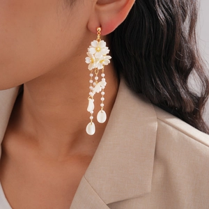 Detailed close-up of floral tassel earrings with faux pearls on an elegant model
