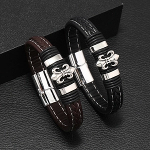 Detail of black and brown braided leather bracelets with fleur-de-lis metal charms