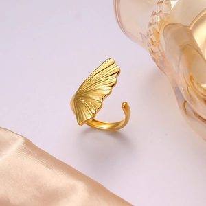 Macro detail of golden ginkgo leaf open ring with textured surface on silk fabric