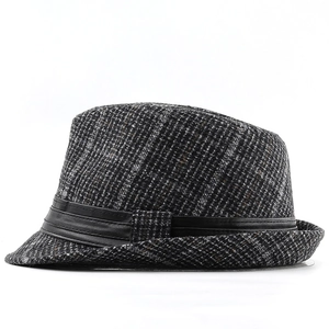 Detail shot of a grey plaid fedora hat featuring a black leather decorative band