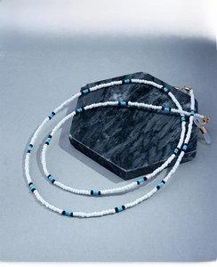 Detail of beaded eyewear chain with blue and black accents on marble display