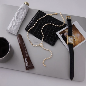 Détail d'un collier en Y doré avec cristaux de zircon rectangulaires en décor lifestyle