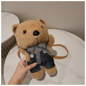 Detail of cute brown plush teddy bear crossbody bag featuring denim overalls and bow