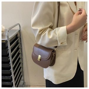 Detailed side view of a brown vintage saddle bag with gold metal buckle on a model