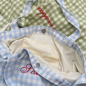 Detail of blue plaid canvas tote with magnetic clasp, inner zipper pocket and embroidery