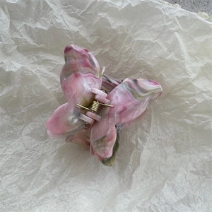 Detail of 3D butterfly hair claw featuring pink marble texture and gold metal spring