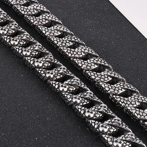 Macro shot of Cuban chain link detail with realistic snake scale texture in dark grey steel
