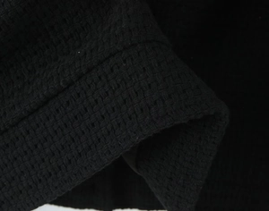 Close-up detail of the black tweed fabric texture and stitching on the women's winter jacket