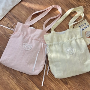 Detail of pink and yellow canvas drawstring bags with lace hearts and bow embroidery