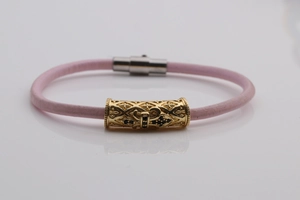 Detail of pink leather bracelet featuring gold hollow pattern tube and black crystal inlay