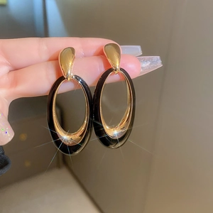 Detail of vintage oval drop earrings featuring black enamel and gold plated finish