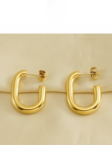 Detailed view of polished 18k gold U-shaped titanium steel earrings on silk