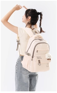 Model wearing a beige ergonomic school backpack with cute cloud plush charm and side pockets