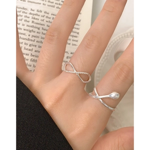 Minimalist S925 sterling silver infinity twist ring worn on finger over book background
