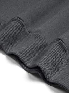 Detail of dark grey knit sweatshirt showing premium ribbed cuff and fabric texture