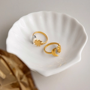 Artistic hammered sun and moon adjustable rings displayed on a white shell ceramic dish