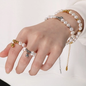 Vue détaillée de bracelets et bagues en perles avec billes dorées portés par un mannequin