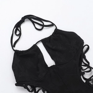 Close-up of black halter jumpsuit with butterfly jacquard fabric and lace-up side detail