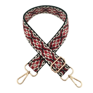 Detail of red and black geometric jacquard bag strap with golden metal swivel hooks