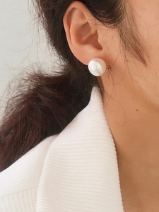 Close-up of a model wearing large white round pearl stud earrings with high luster