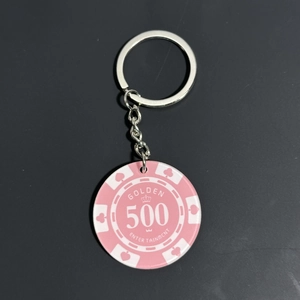 Detail of pink acrylic poker chip keychain with crown motif and golden engraving
