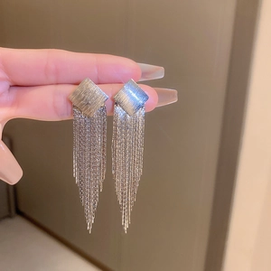 Close-up of silver long tassel earrings with brushed square studs and V-shaped metal chains