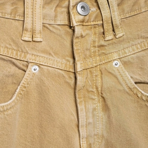 Nahaufnahme gelber Jeans mit Metalldetails und feiner Denim-Struktur am Bund