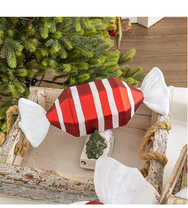 Close-up of red and white striped Christmas candy ornament with glitter in a wooden tray