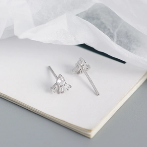 Macro detail of S925 sterling silver stud earrings with geometric zircon inlay on paper