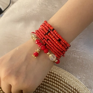 Detail of bohemian red multilayered beaded bracelet with gold accents on model wrist