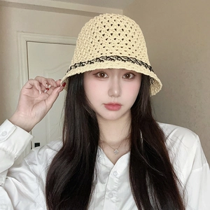Detail of hand-crocheted beige straw bucket hat with black woven band on model
