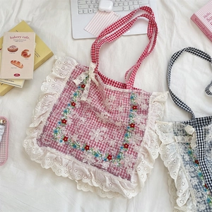 Detailed close-up of floral embroidery and white lace trim on a plaid canvas tote bag