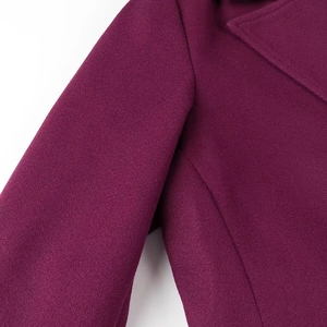 Détail de l'épaule et du revers d'un manteau en laine magenta montrant la texture du tissu