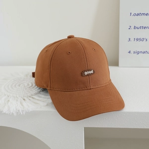 Close-up of deep brown canvas baseball cap featuring a 'good' embroidered patch detail