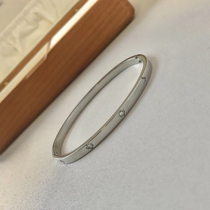 Silver stainless steel bangle with floral engravings and zircons on grey background