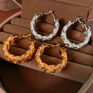Macro shot of gold and silver woven hoop earrings inside a premium velvet jewelry box