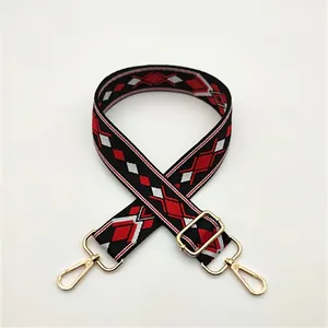 Close-up of adjustable woven shoulder strap with red and black geometric pattern and gold clips