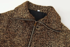 Detail of metallic textured bomber jacket showing the zip collar and tassel fabric