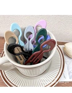 Macro shot of colorful U-shaped plastic hair pins placed in a white ceramic cup