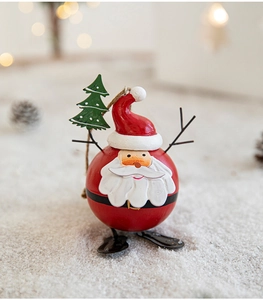 Macro shot of spherical Santa figurine with Christmas tree and polished metal finish