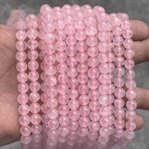 Close-up of natural rose quartz round beads on a pink cord held by hand