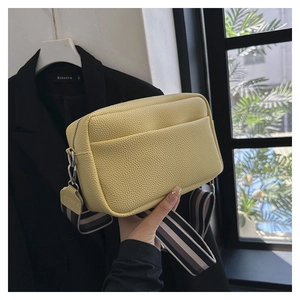 Détail du sac bandoulière jaune en cuir grainé avec une large bandoulière rayée