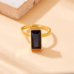 Golden adjustable ring with a large rectangular black gemstone on a stone aesthetic display