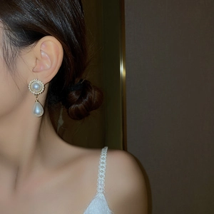 Gros plan de boucles d'oreilles vintage en perle goutte avec détails dorés sur modèle