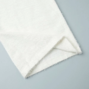 Close-up of soft white long-pile mohair knit fabric showing texture on sweater cuffs
