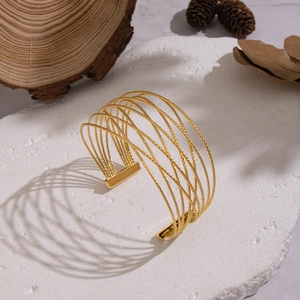 Detailed shot of gold multilayer mesh cuff bracelet on rustic natural stone background