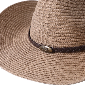 Détail d'un chapeau de cowboy en paille tissé avec emblème de taureau en bronze sur cuir
