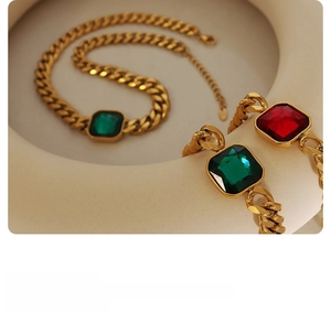 Close-up of gold Cuban chain jewelry set featuring emerald and ruby square crystals
