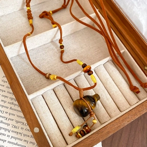 Macro detail of Tiger Eye Hulu pendant necklace with polished stone texture and woven cord