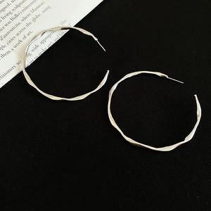 Macro view of silver twisted hoop earrings with irregular streamline design and metallic shine